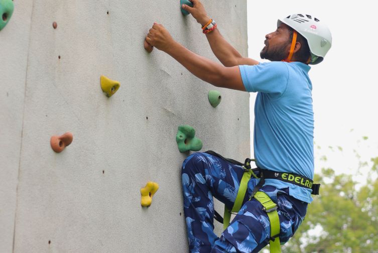 Close-up of guest climbing the artificial rock wall at Roadies Rostel ARC Resort adventure park in Ahmedabad