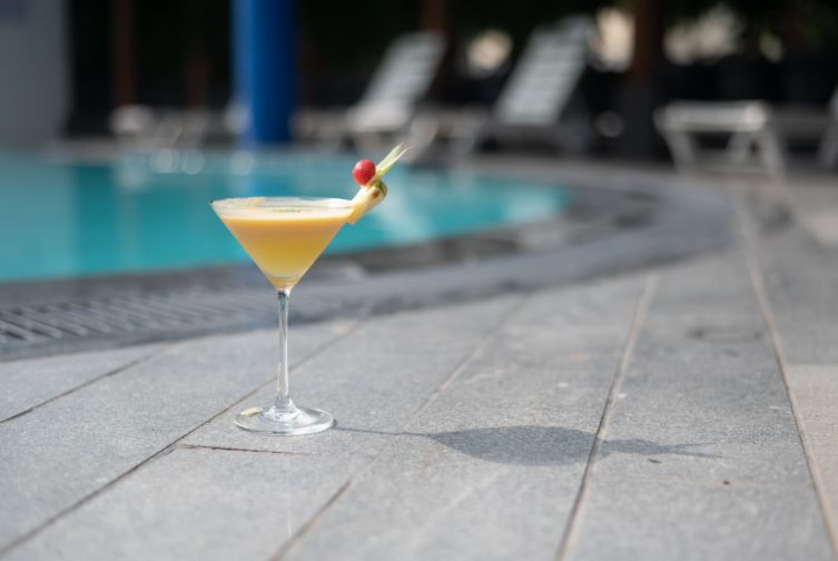 Refreshing yellow mocktail in a martini glass placed poolside at Roadies Rostel ARC Resort near Ahmedabad
